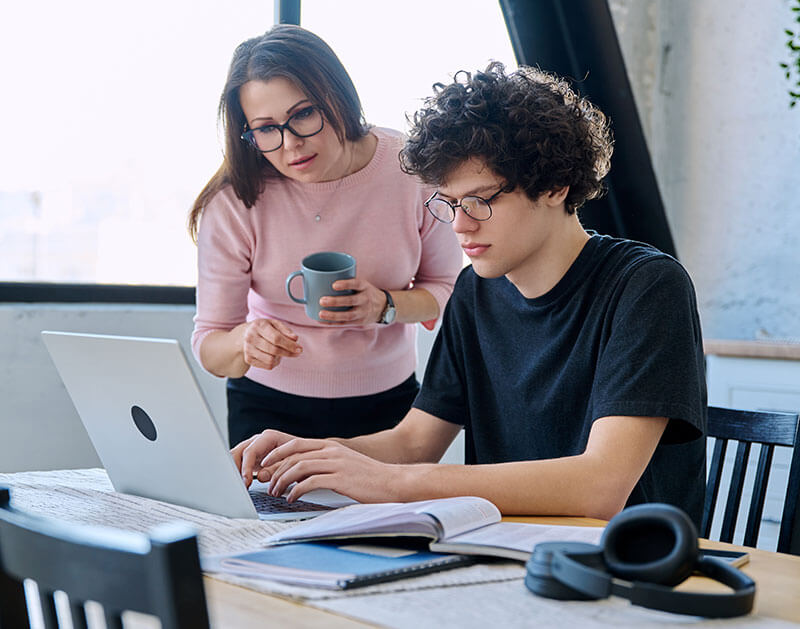Mother observing her son working on his laptop